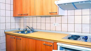 A kitchen with wooden cabinets, a sink, a stove, and tiled walls. - Snow covered Apartment in Sierra Nevada (Sierra Nevada)