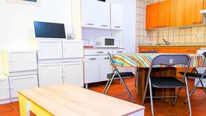 A compact kitchen with white cabinets, a microwave, a small table, and a foldable chair. - Snow covered Apartment in Sierra Nevada (Sierra Nevada)