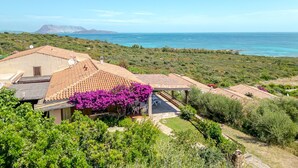 A villa with a patio, a view of the sea, and a mountain in the background. - Villetta Oleandro with Sea View, Private Terrace and Garden (San Teodoro)