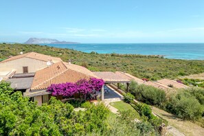 A villa with a patio, a view of the sea, and a mountain in the background. - Villetta Oleandro with Sea View, Private Terrace and Garden (San Teodoro)