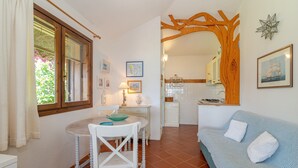 A cozy living room with a dining table, a sofa, and a kitchen in the background. - Villetta Oleandro with Sea View, Private Terrace and Garden (San Teodoro)