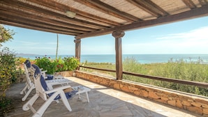 A covered outdoor seating area with stone flooring, wooden beams, and a view of the sea. - Villetta Oleandro with Sea View, Private Terrace and Garden (San Teodoro)