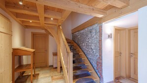 Una escalera de madera con un muro de piedra, una mesa de madera y una puerta.