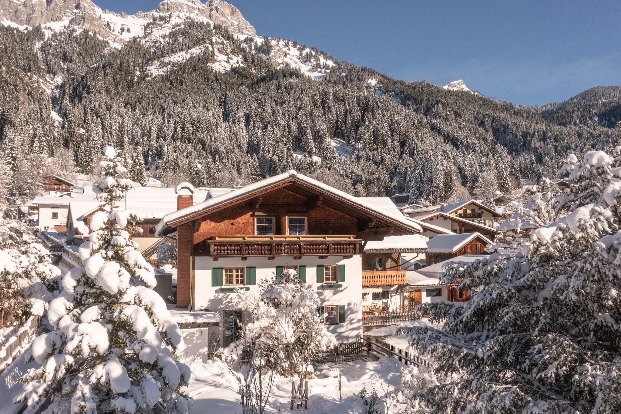 A chalet-style building with a sloped roof, surrounded by snow-covered trees and mountains.