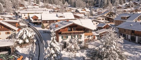 A snow-covered village with wooden buildings and a ski lift.
