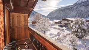 Un balcón de madera con vistas a un paisaje montañoso nevado y un edificio con un letrero que dice "Bacherei".