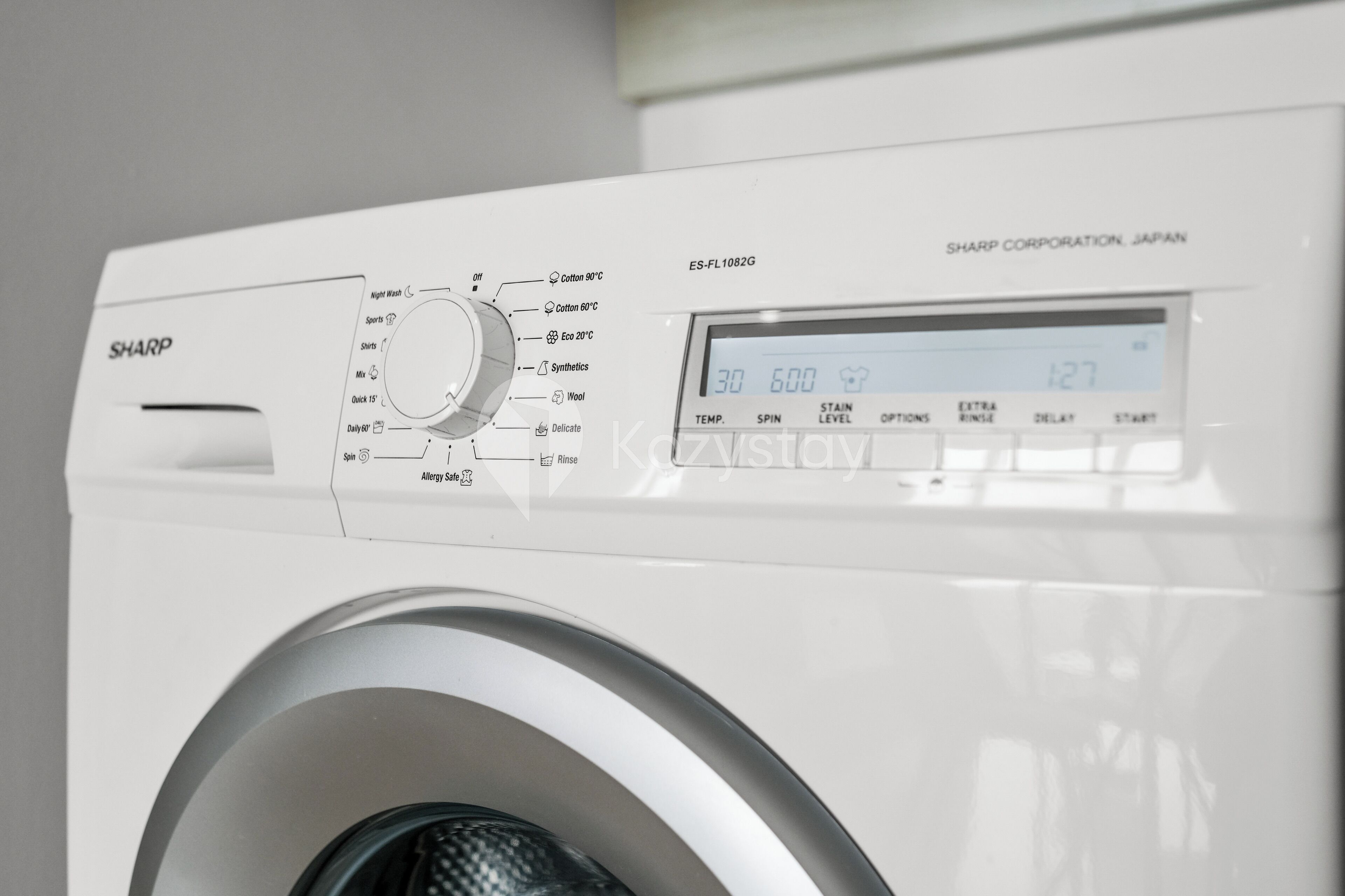 A white Sharp washing machine with a digital display and control panel.