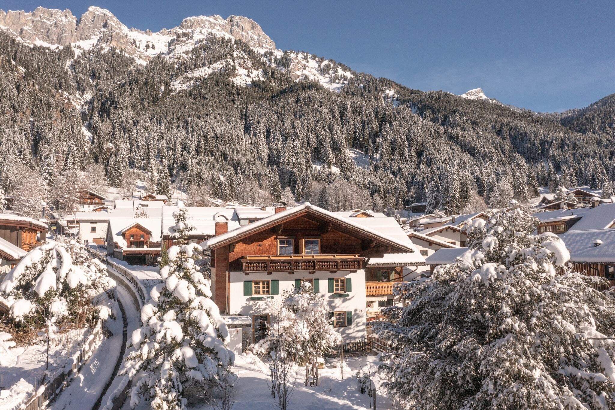 A snow-covered mountain village with wooden buildings and a clear view of the mountains in the background.