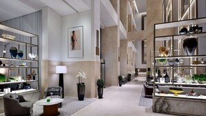 Un'ampia hall con arredamento moderno, un'area salotto centrale ed esposizione di oggetti decorativi.