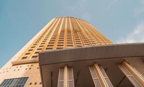 A tall building with a modern architectural design, featuring a series of vertical lines and rectangular windows. - The Grand Burj Panorama • 3BR Luxury Fountain Views + Balcony (Dubai)