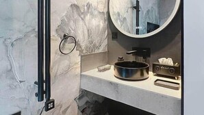 A modern bathroom with a marble wall, a round mirror, a towel rack, and a sink with a basin. - T2 Luxury Canet • Beach 50m - Romantic stay ❤️ Love room (Canet-en-Roussillon)