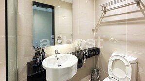 Casa de banho moderna com lavatório branco, espelho, sanita e secador de mãos.