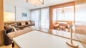 A modern living room with a sofa, a dining table, and a large window. - Bernardi Apartment (Caprile)