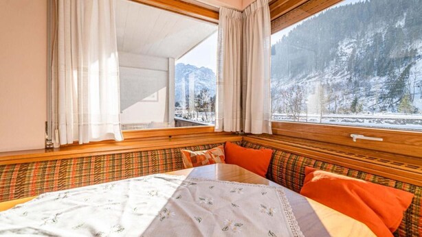 A room with a bed, a window with curtains, and a view of a snowy mountain. - Bernardi Apartment (Caprile)