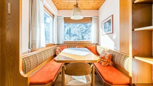 A cozy cabin interior with wooden walls and a large window offering a snowy mountain view. - Bernardi Apartment (Caprile)