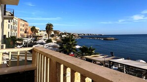 A coastal view with buildings, a pier, and a clear sky.
