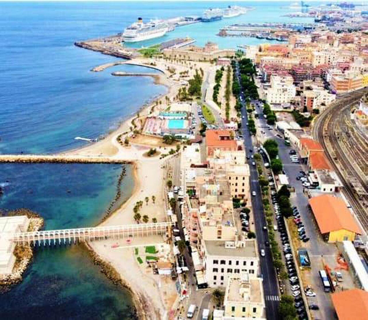 Vista aérea de una ciudad costera con un puerto deportivo, una playa y una vía de tren.