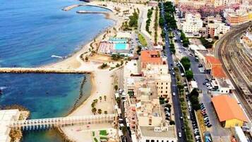 Vista aérea de una ciudad costera con un puerto deportivo, una playa y una vía de tren.