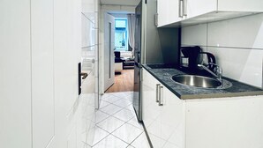 Una cucina moderna con mobili bianchi, un lavello in acciaio inossidabile e un piano di lavoro nero.