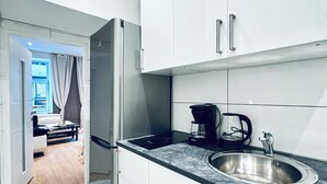 Una cucina moderna con mobili bianchi, un lavello in acciaio inossidabile e una macchina per caffè.