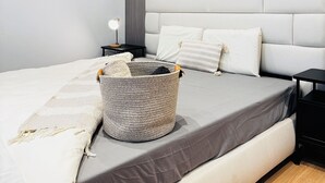 Una camera da letto moderna con un letto grande, uno specchio rotondo, un comodino con una lampada e un muro decorativo.