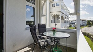 A balcony with a round table and two chairs, overlooking a white building with a balcony. - Haus Concordia - Holiday apartment on the Mönchgut - Haus Concordia vacation apartment (Mönchgut)