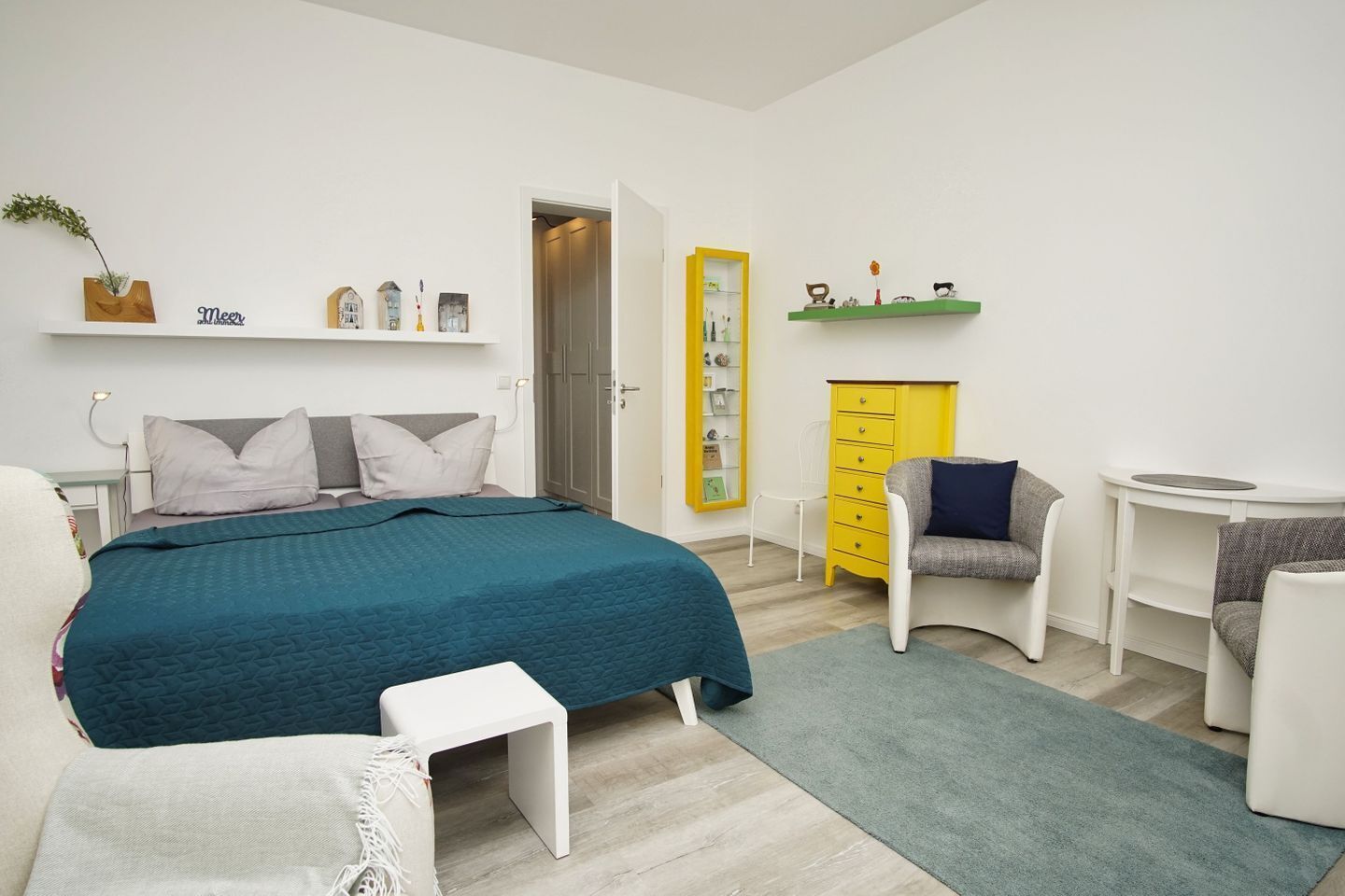 A modern bedroom with a bed, bedside tables, a desk, a chair, and a wardrobe.