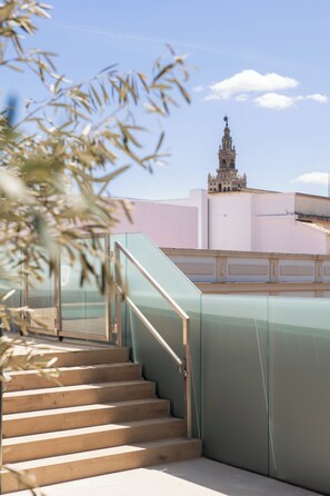 A staircase leading to a building with a clock tower, a glass railing, and a clear sky. - Líbere Seville Plaza Nueva (Seville)