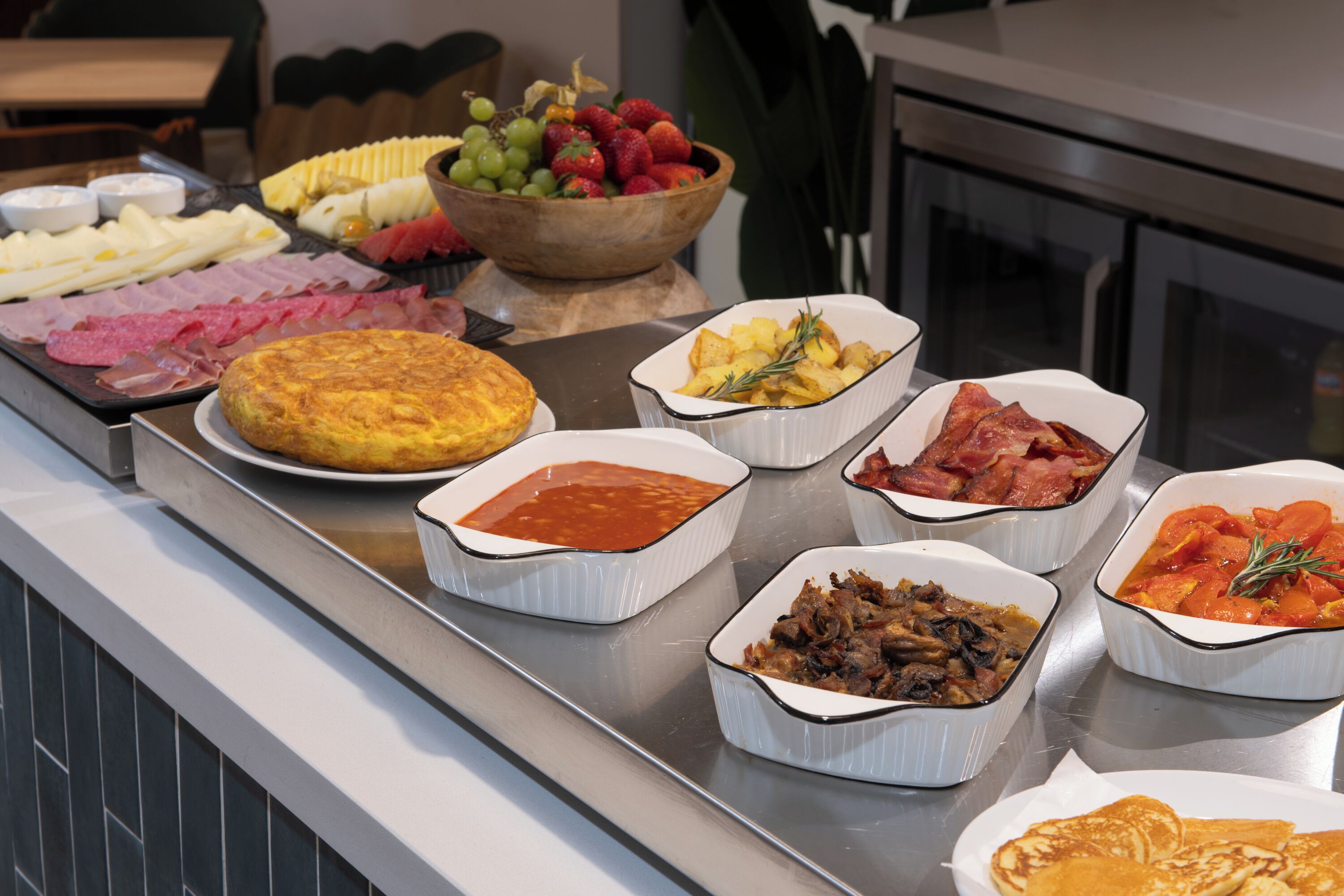 A buffet with various dishes including meats, fruits, and vegetables.