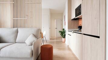 A modern living room with a sofa, ottoman, and a wooden partition.