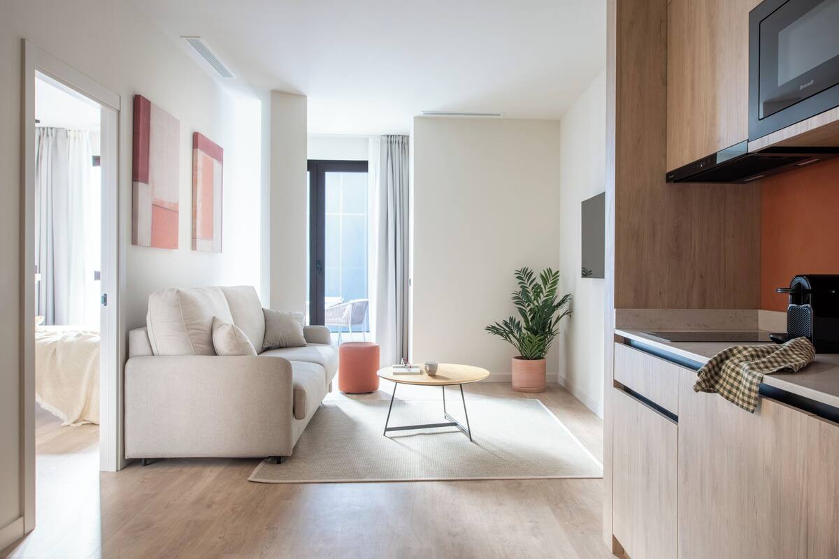 A modern living room with a sofa, a round coffee table, and a potted plant.