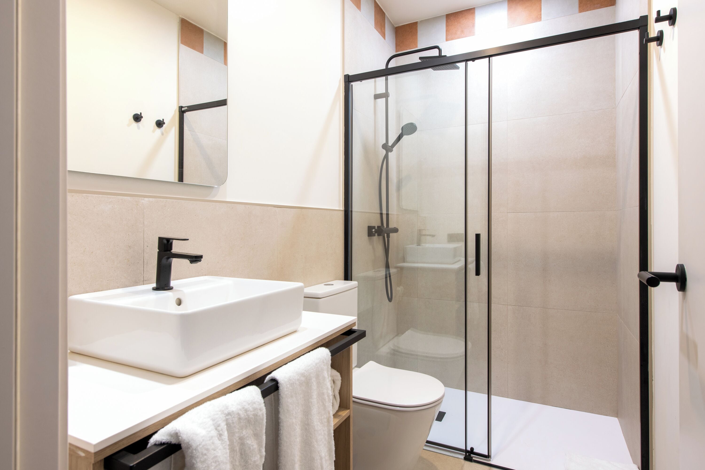 A modern bathroom with a glass-enclosed shower, a white sink, and a toilet.