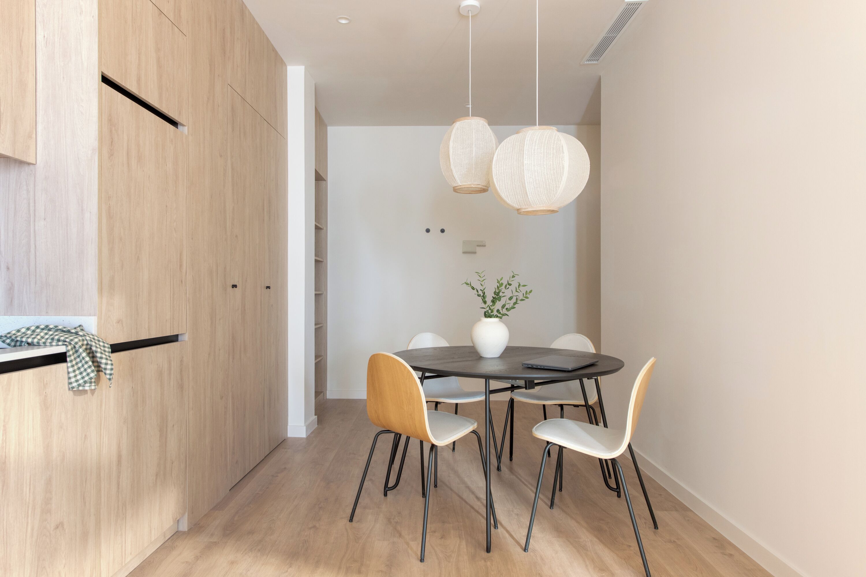 A modern dining area with a round table, four chairs, and two hanging light fixtures.