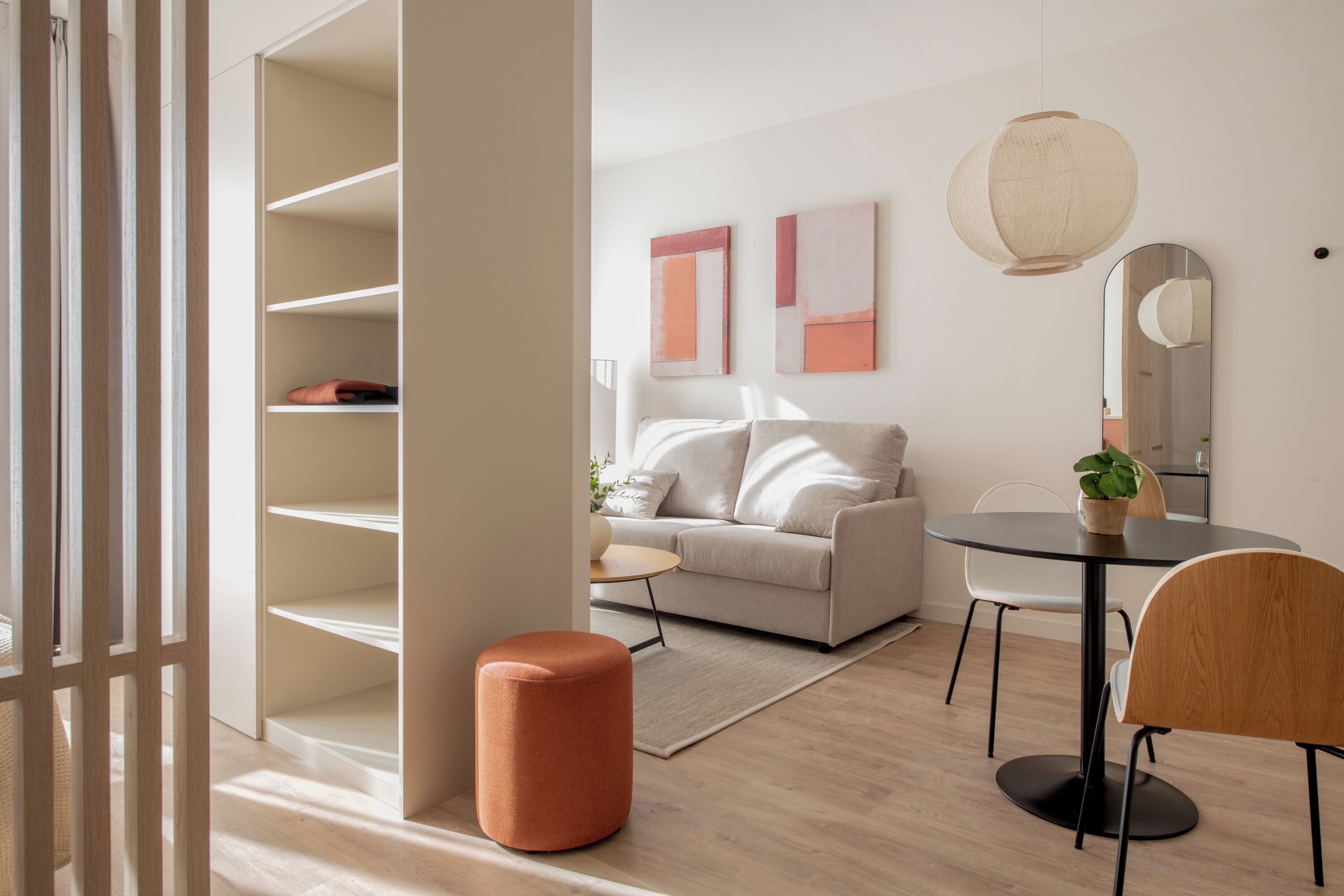 A modern living room with a sofa, a round table, and a mirror.