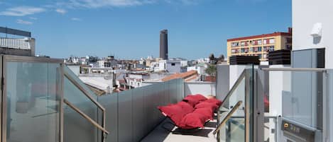 A modern building with a glass facade, a red seating area, and a view of the cityscape.