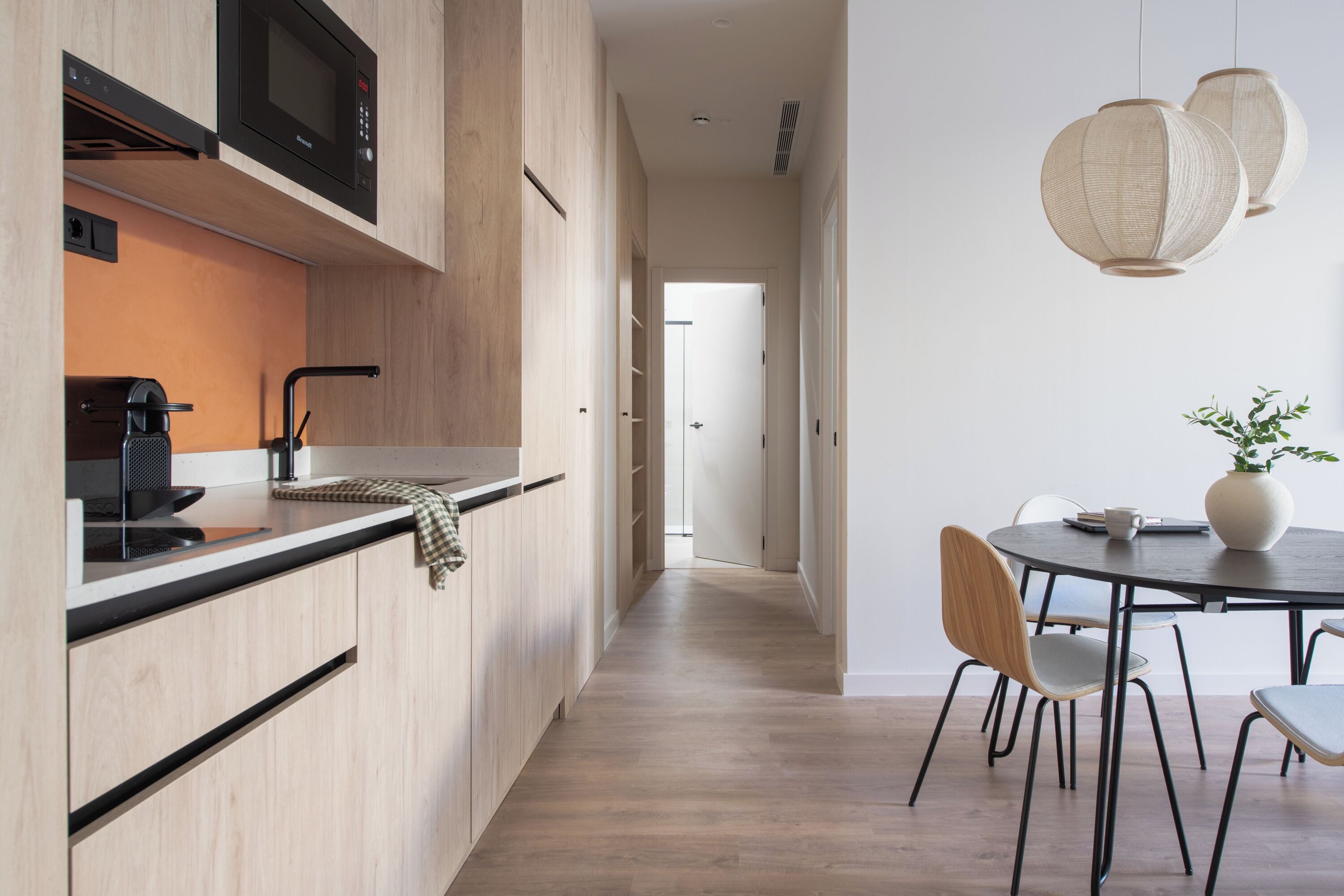 A modern kitchen with a microwave, coffee machine, and a dining area with a table and chairs.