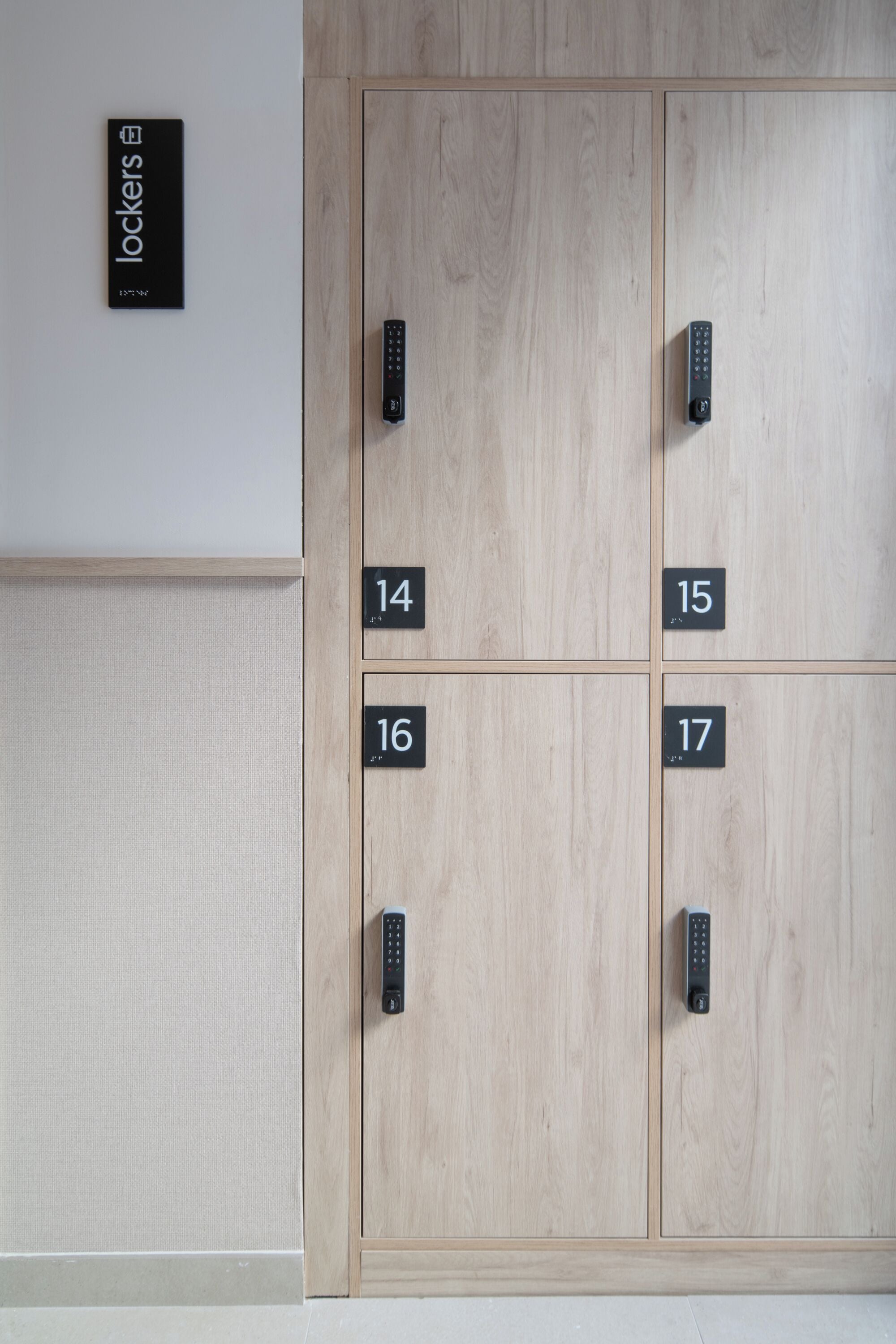 Een rij lockers met de nummers 14 tot en met 17, een bord erboven met de tekst 'lockers', en een afstandsbediening hangend aan de muur.