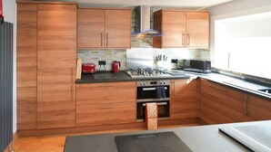 Uma cozinha moderna com armários de madeira, fogão a gás e forno embutido.