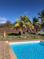 Una piscina al aire libre, sombrillas, sillones reclinables de piscina