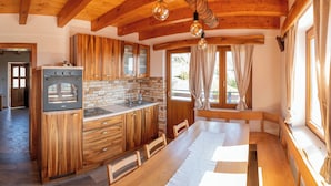 A kitchen with wooden cabinets, a built-in oven, and a window with curtains. - Vineyard cottage Mehak (Sevnica)