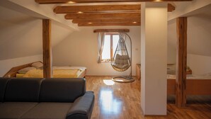 A cozy attic bedroom with wooden beams, a hanging chair, and a bed with a yellow blanket. - Vineyard cottage Mehak (Sevnica)