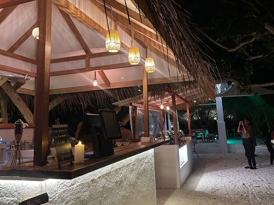 An outdoor bar area with a thatched roof, wooden beams, and hanging lantern-style lights.
