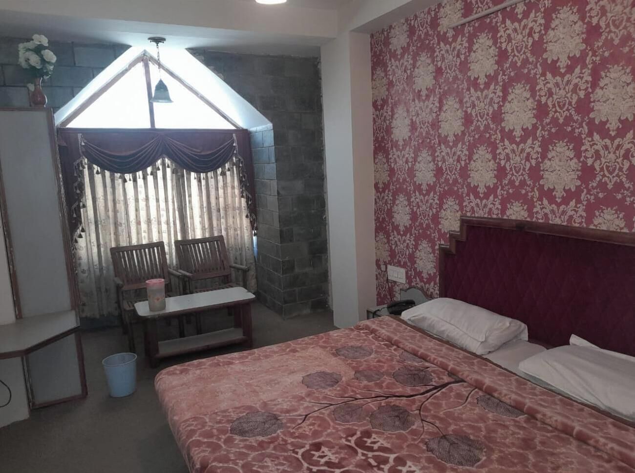 Une chambre à coucher avec un lit, un bureau, une chaise et une fenêtre avec des rideaux.