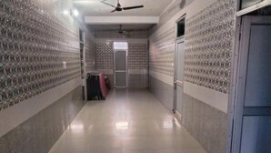 A corridor with tiled walls and floor, a ceiling fan, and a door at the end. - Hotel Sharma Guest House  (Naina Devi)