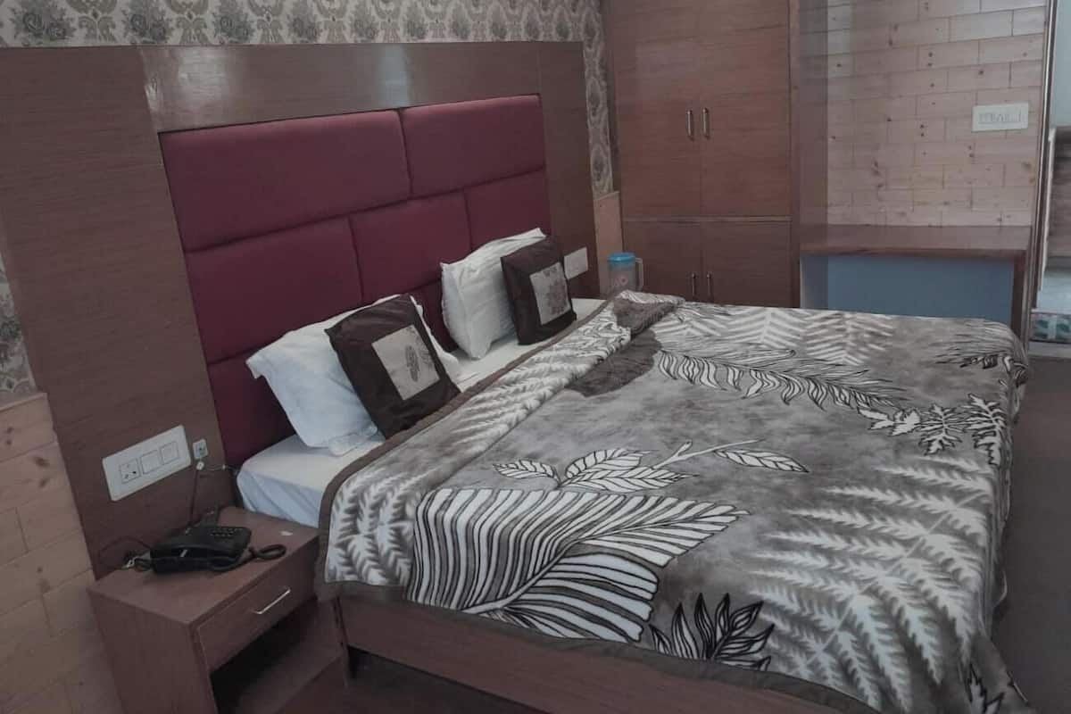 A bedroom with a large bed, a nightstand, a wardrobe, and a patterned bedspread.