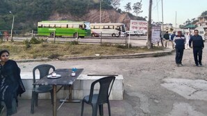 A bus station with a green bus, a signboard, and a table with chairs. - Hotel Sharma Guest House  (Naina Devi)