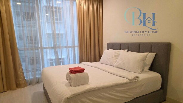 Una cama bien tendida con sábanas blancas y un cabecero gris en una habitación de hotel.