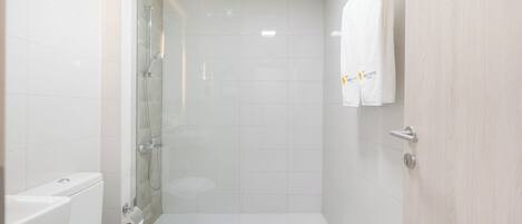 A small, modern bathroom with a glass shower enclosure, a toilet, and a sink.