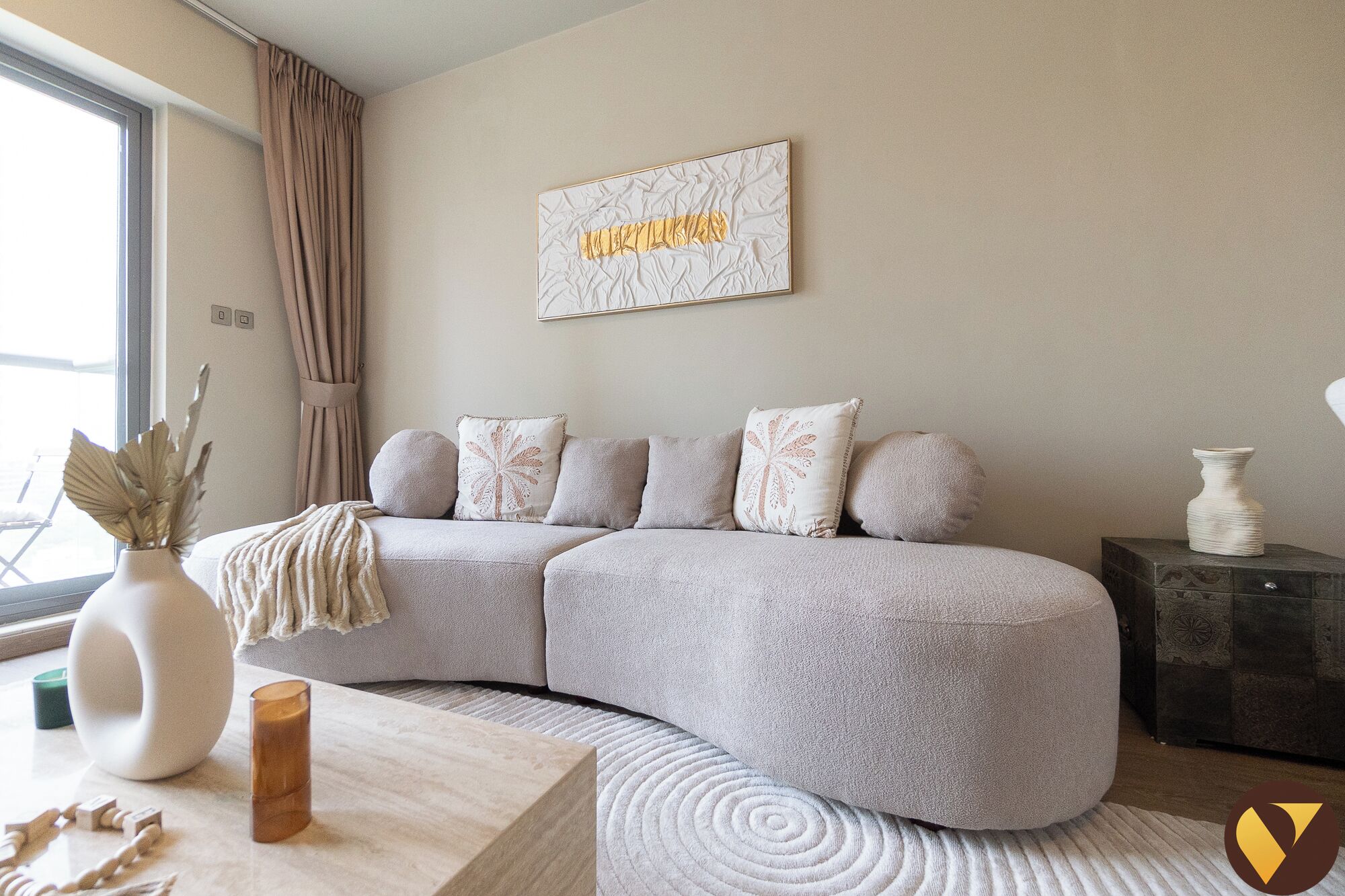 A modern living room with a curved sectional sofa, a coffee table, and a decorative vase.