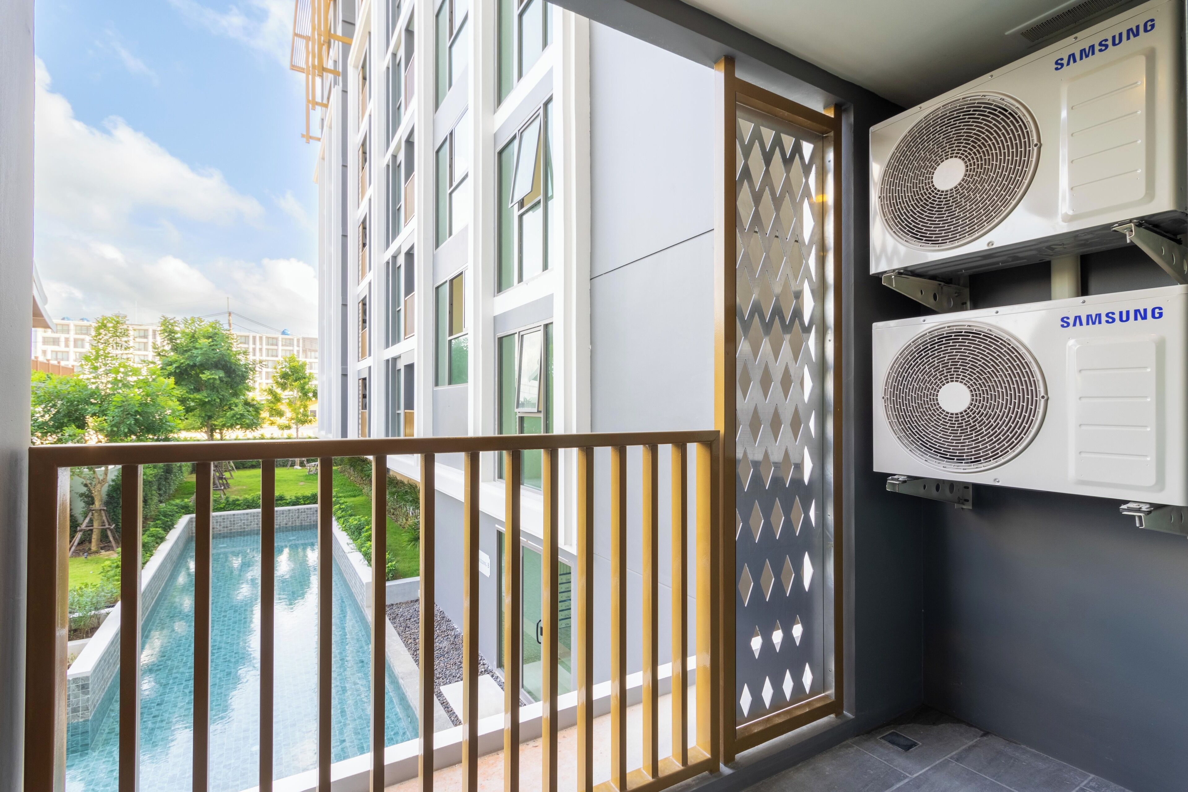 Un balcon avec piscine, des climatiseurs et une vue sur un quartier résidentiel.